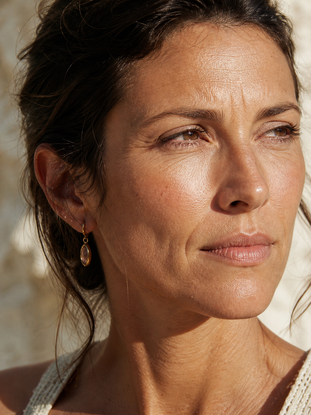 Close-up of a woman's face in direct sunlight, showing fine lines and texture from years of UV exposure